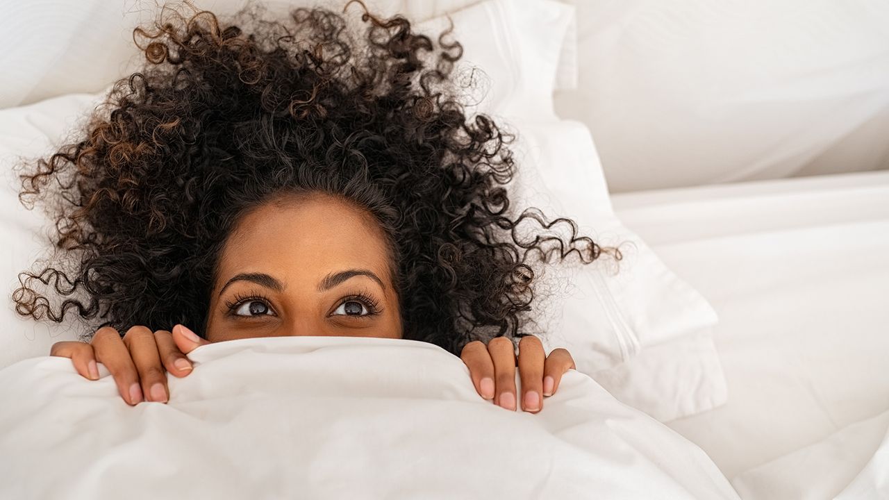 Best duvet: woman pulling duvet up over her face