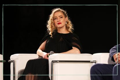 Amber heard sat on a sofa on stage during a talk