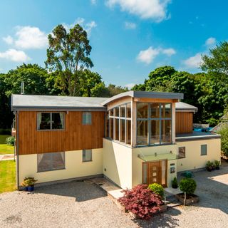 house with sloping roof top wooden walls and grass lawn