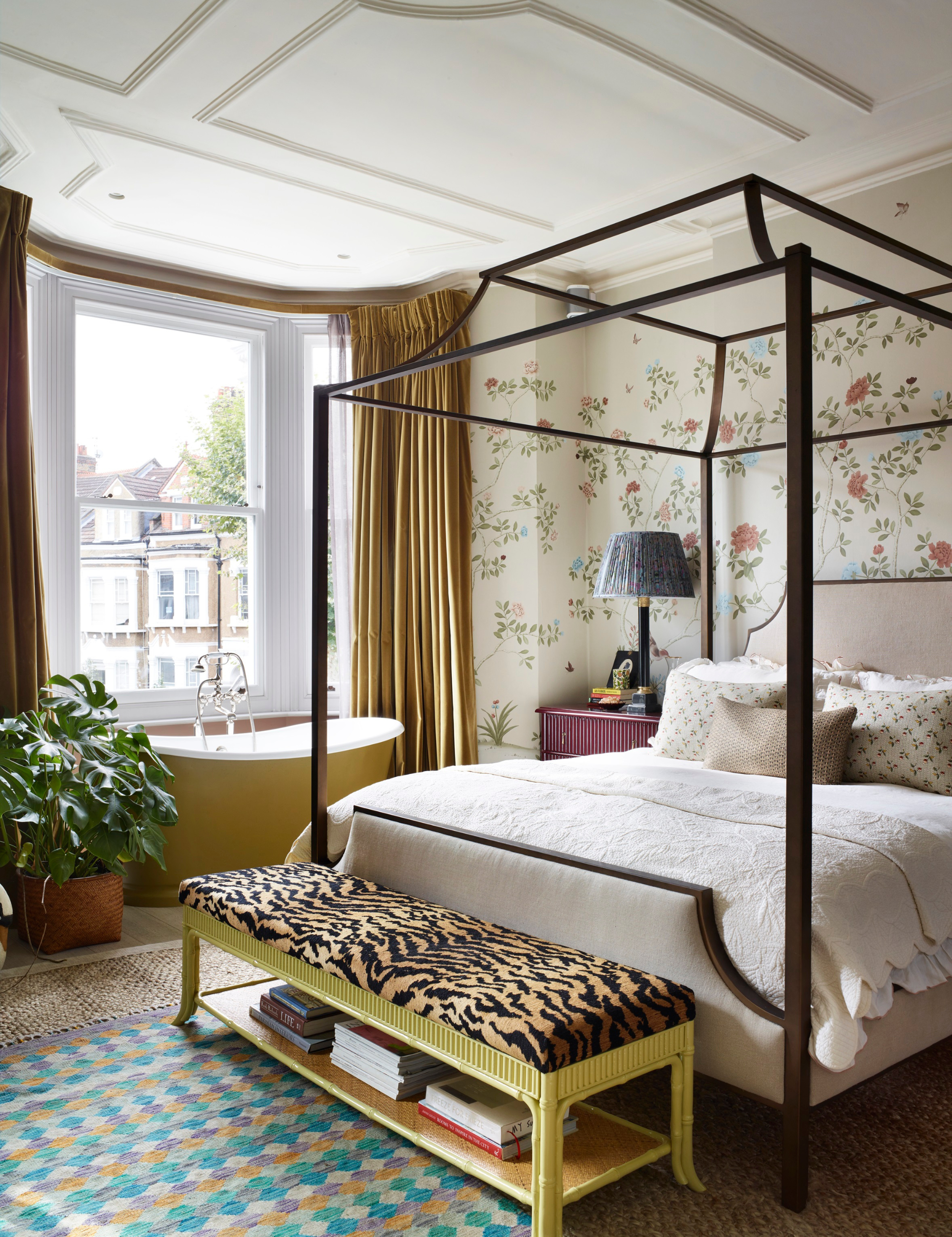 Eclectic bedroom featuring a four-post bed, yellow clawfoot tub, and tiger-striped storage bench