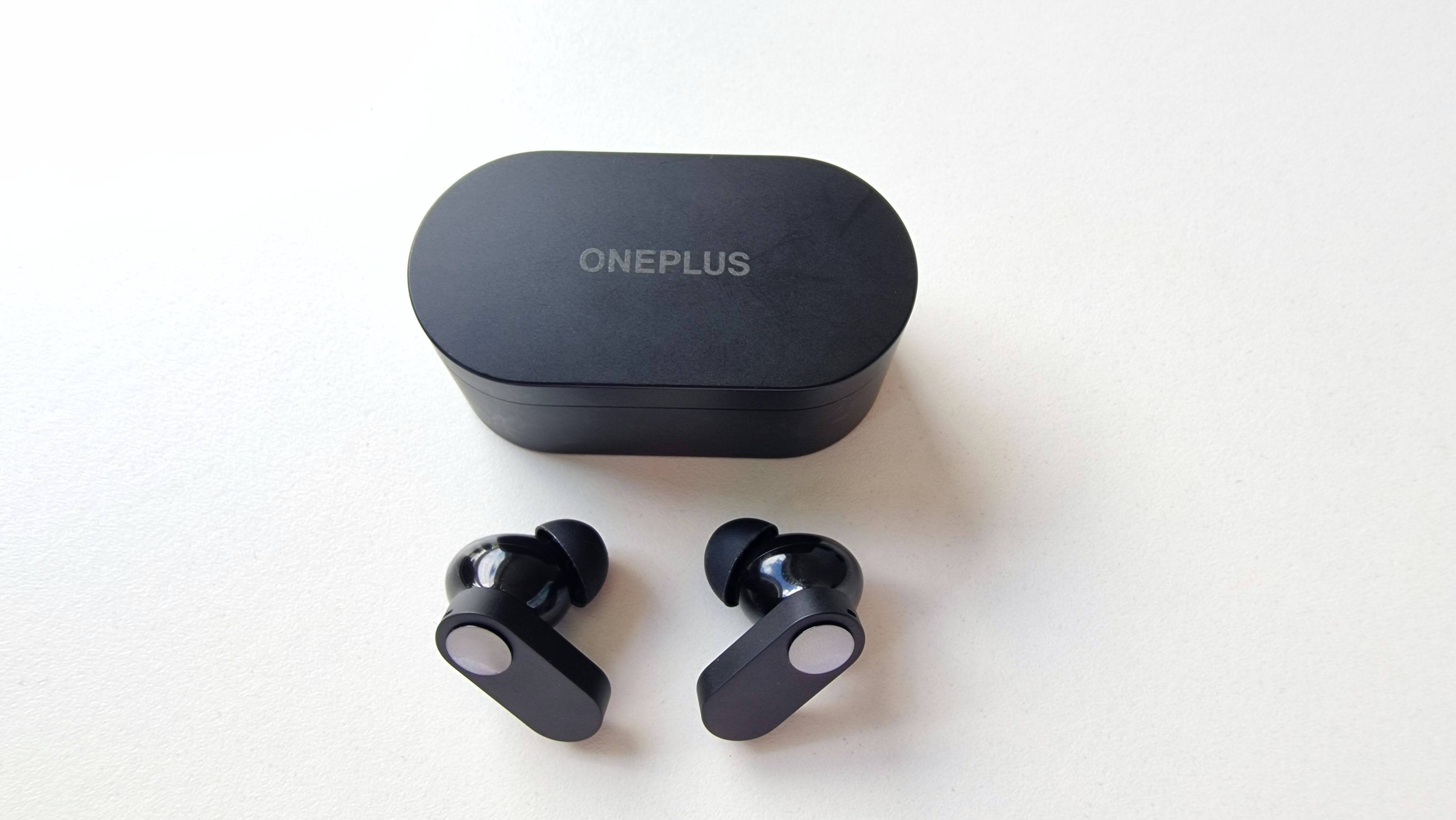 Ett par OnePlus Nord Buds sett uppifrån ligger på ett bord framför laddningsfodralet
