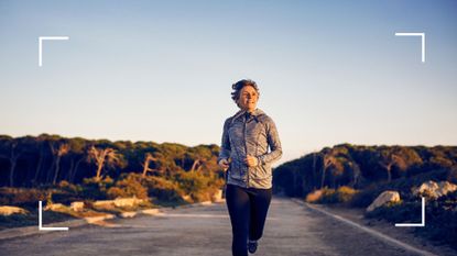 Woman running along road with sun rising behind her, looking forward, exploring slow running benefits