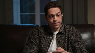 Pete Davidson sitting on a couch in Bupkis.
