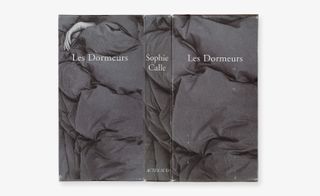 Front and back cover of the book Les Dormeurs by Sophie Calle, laid flat, grey scale, duvet cover and a persons hand poking out of the covers