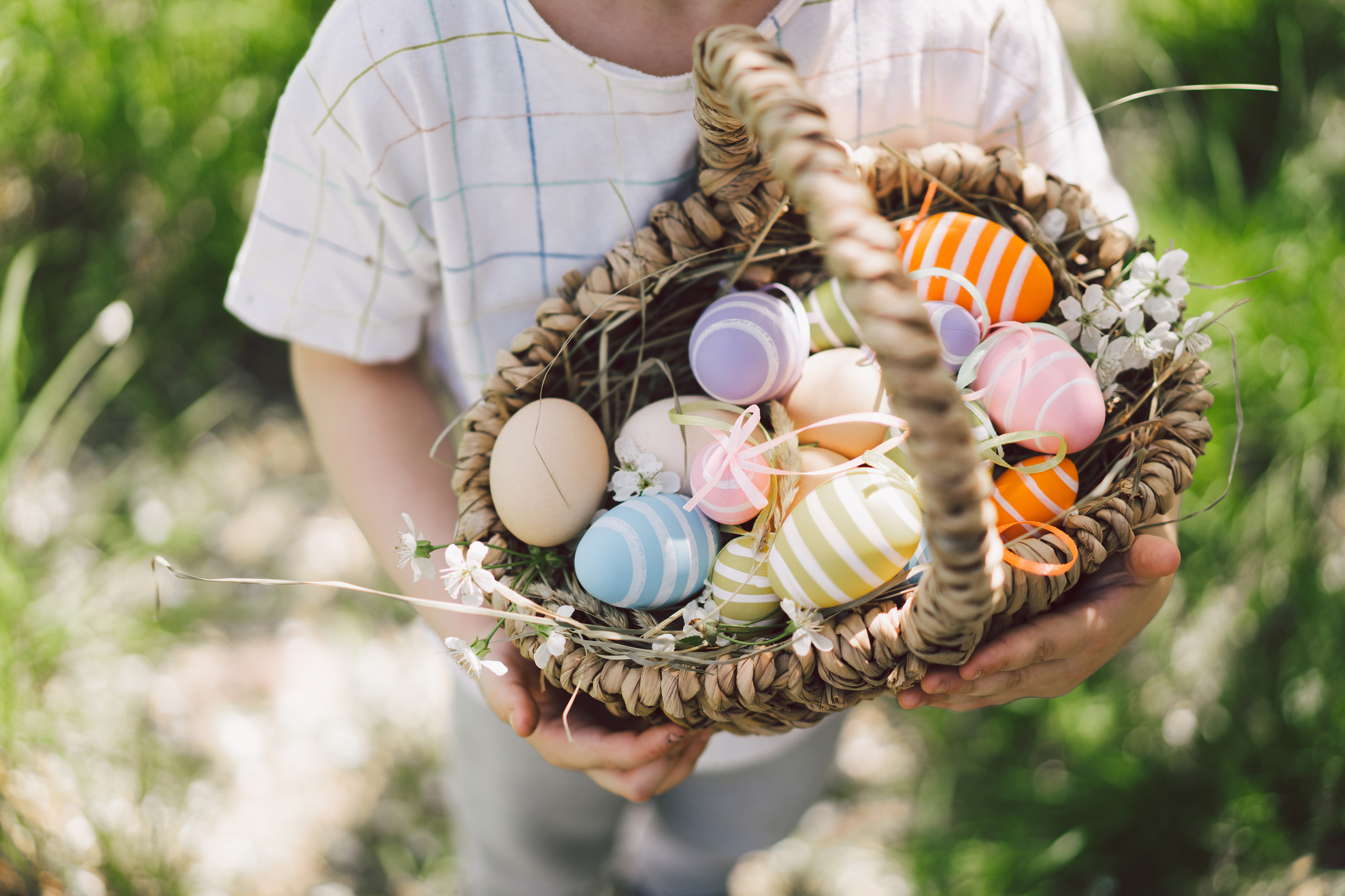 A child carrying an Easter basket full of colourful, pastel Easter eggs.