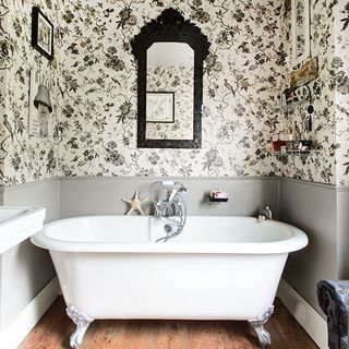 bathroom bathtub with wallpaper on wall and wooden flooring