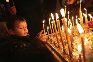 A child lights a candle in church.