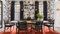 A dining room with patterned wallpaper, overhead lighting and an area rug