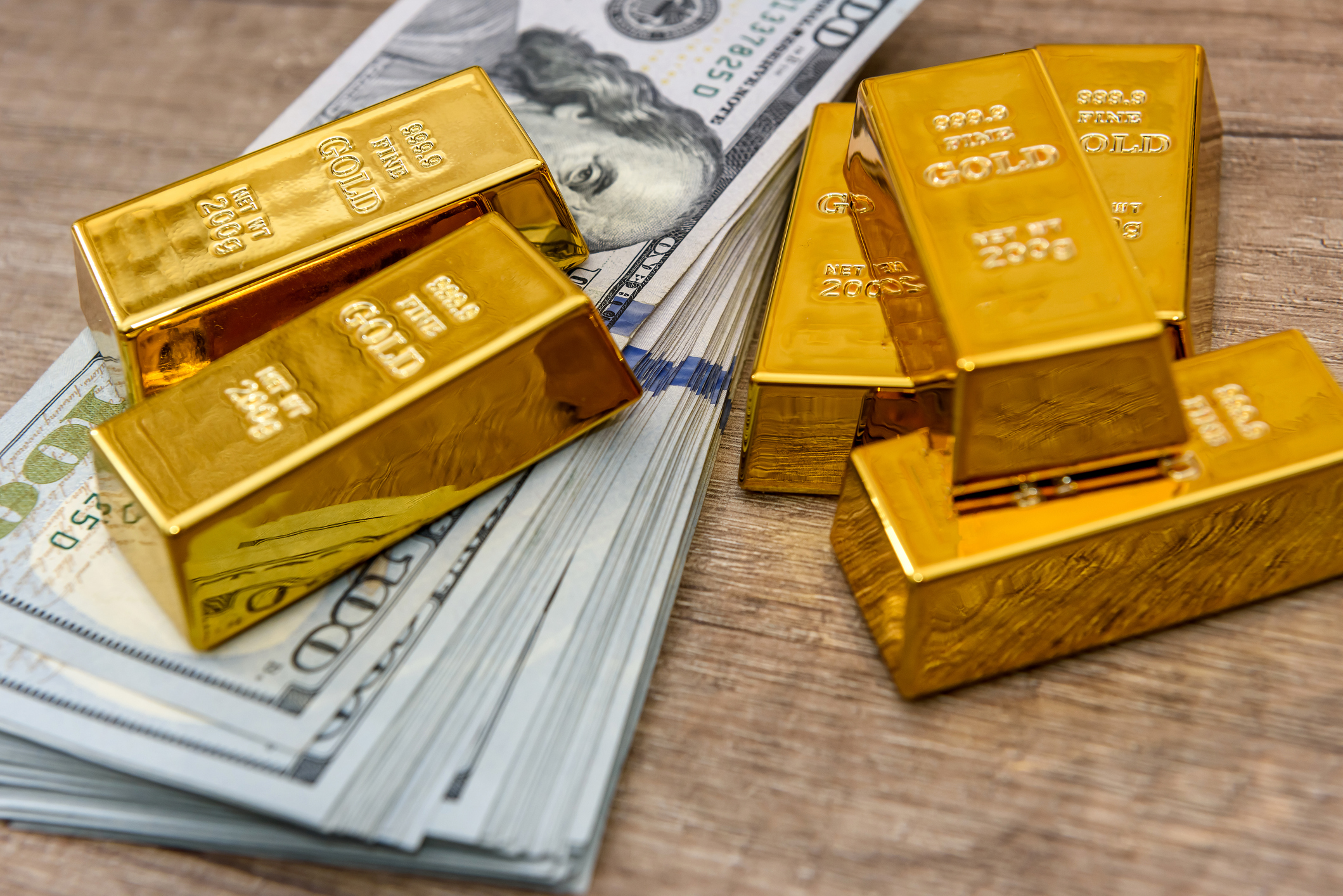 Gold bars with hundred dollar banknotes as background