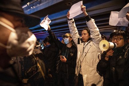 People hold signs amidst continuing protests in China regarding COVID policies. 