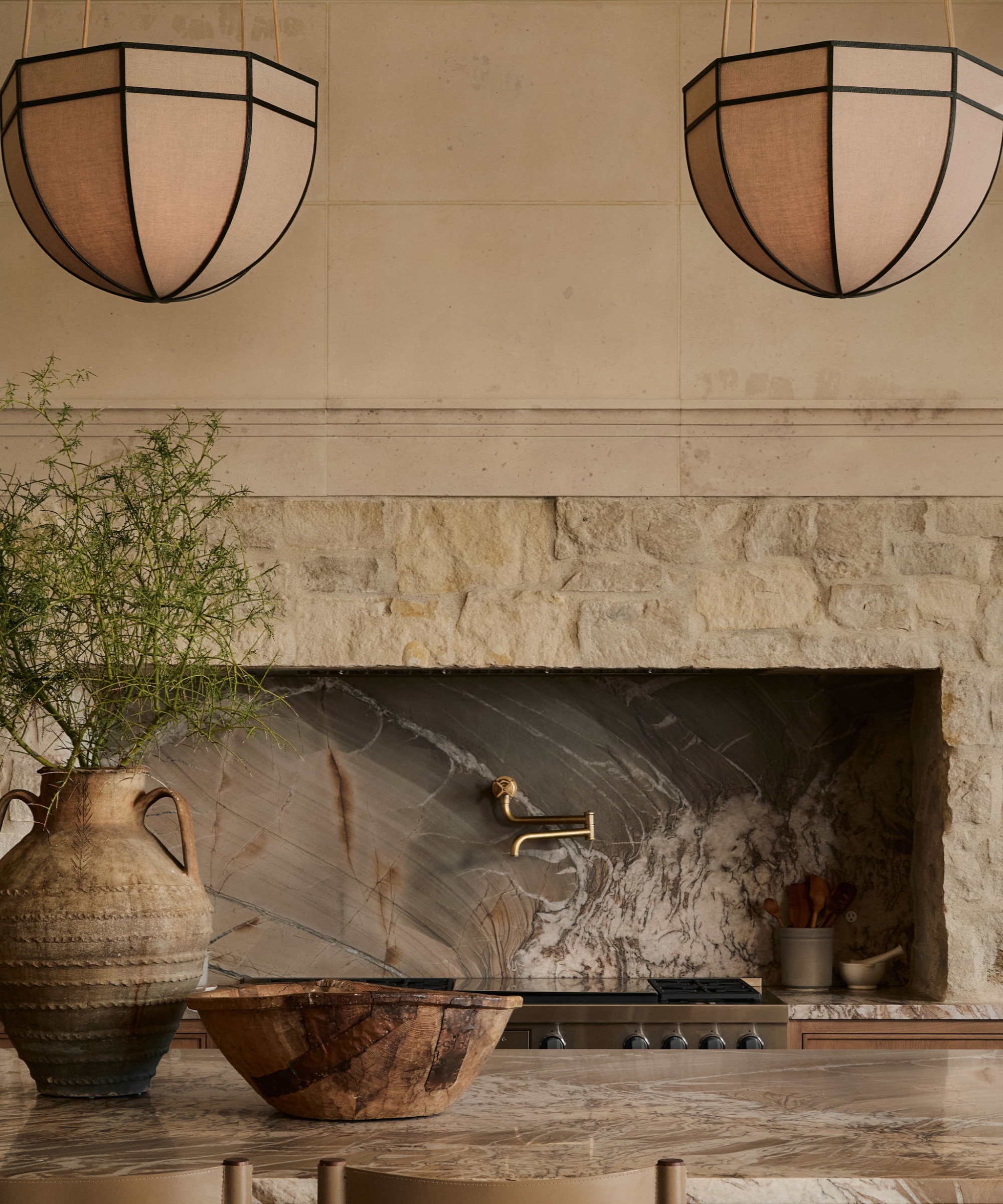 A neutral kitchen with stone countertops and an exposed stone range surround