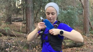 Runner pulling a soft water bottle out of her running vest