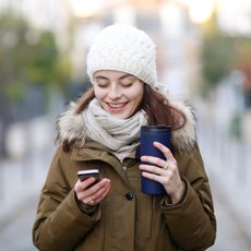 Young woman in coat scarf and hat on cell phone