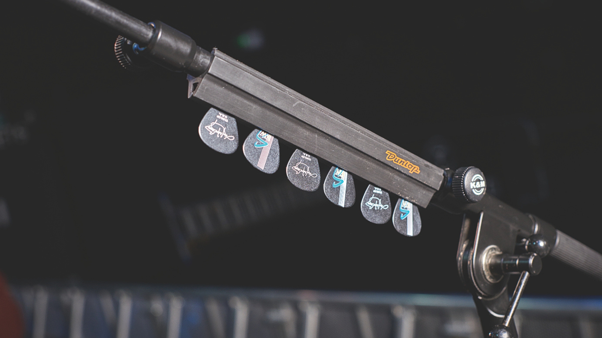A selection of guitar picks in a holder on a microphone stand