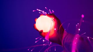 Hand holding glowing sphere with shooting off purple ribbons of light