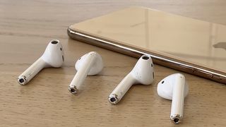 AirPods earbuds and AirPods 2 earbuds with a gold iPhone XS in the background