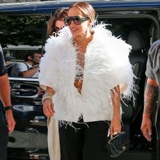 Jennifer lopez wears a fur white top, black bermuda shorts, and a black chanel bag.