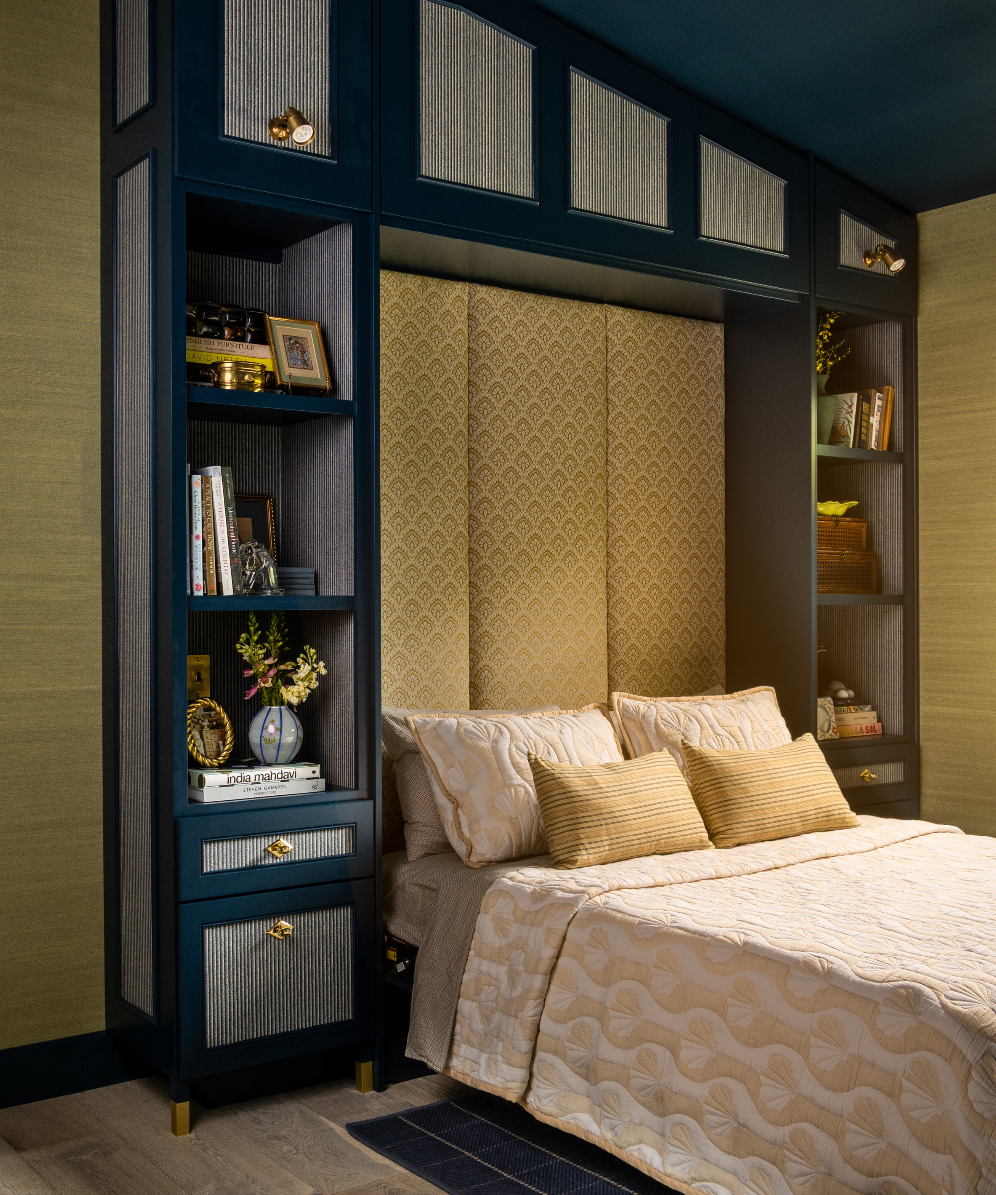 a room with built-in shelving and a murphy bed, gold grass cloth wallpaper, and blue shelves