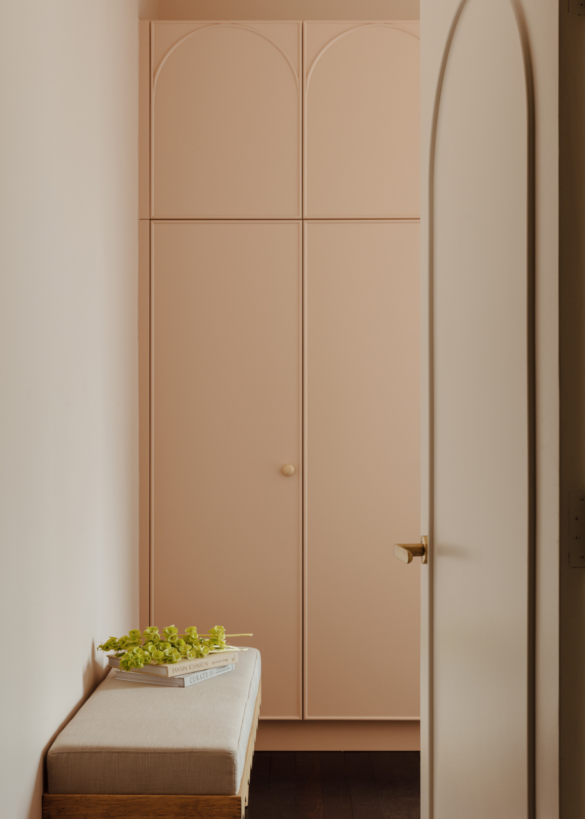 A light pink wardrobe in a walk in closet with a bench