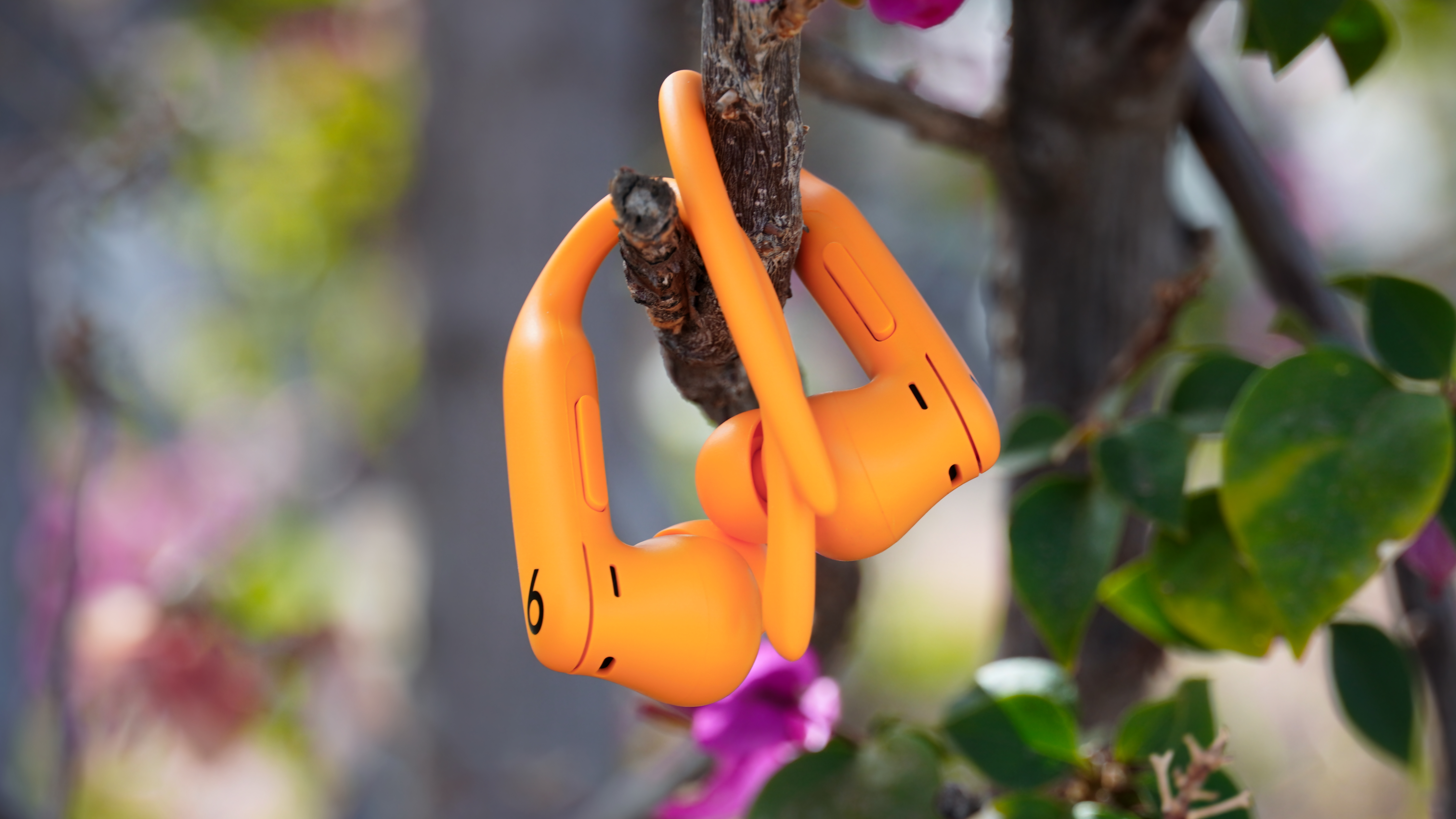 The orange Powerbeats Pro 2 next to the Navy original Powerbeats Pro.