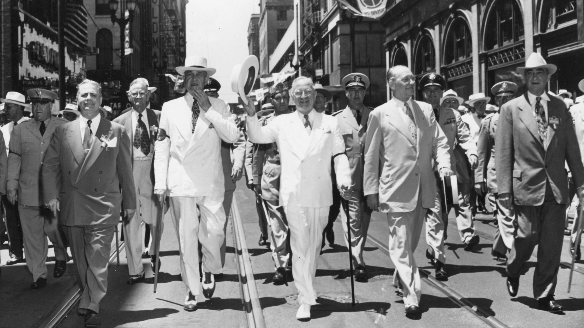 President Harry Truman marching down a main street with officials