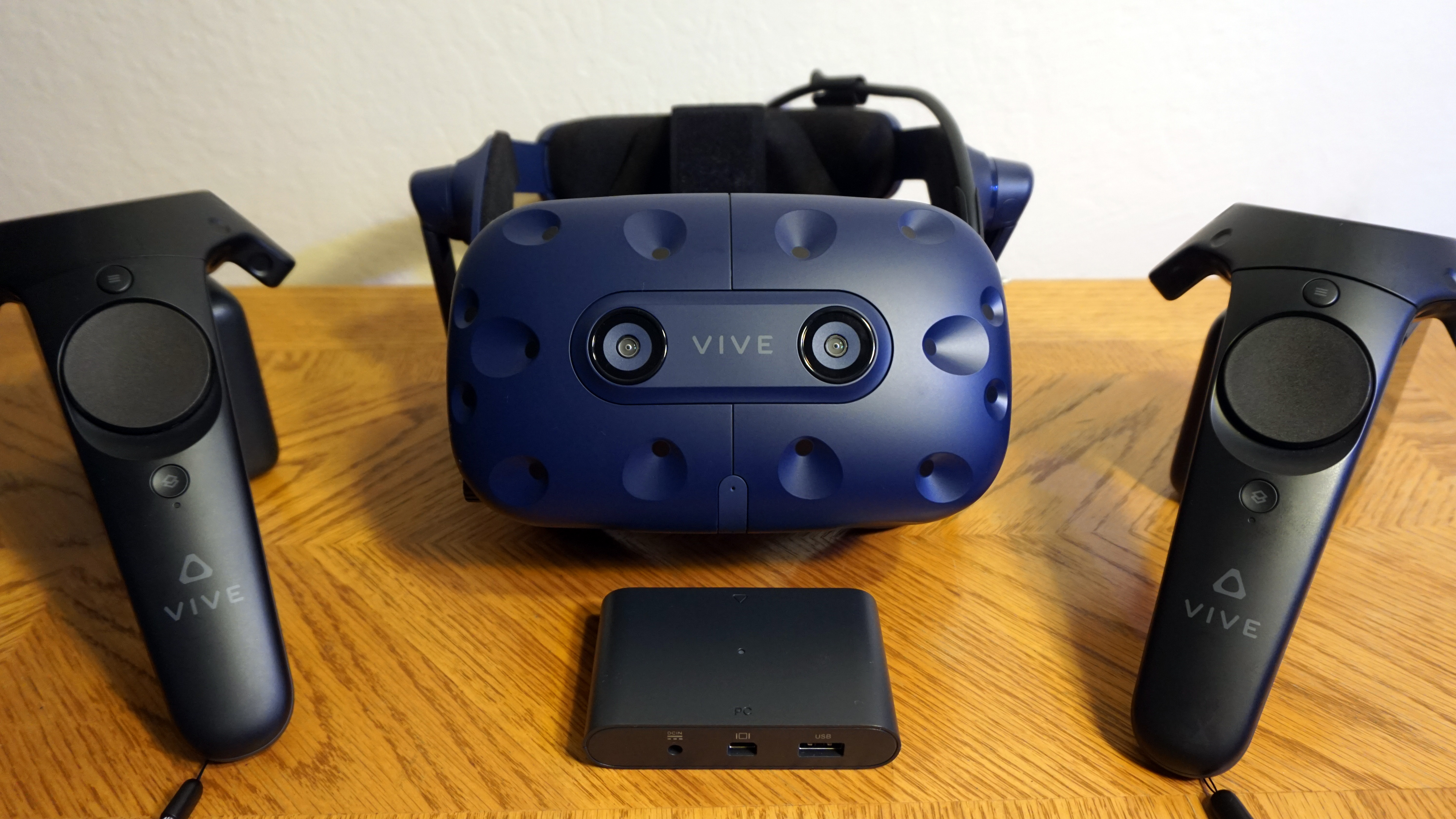 Ett HTC Vive Pro står uppställt på ett bord bredvid sina tillhörande kontroller.