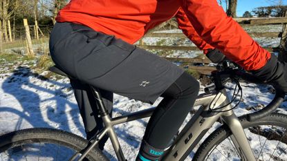 The Rab Cinder Kinetic Waterproof shorts worn on a rider on a bike with snow in the background