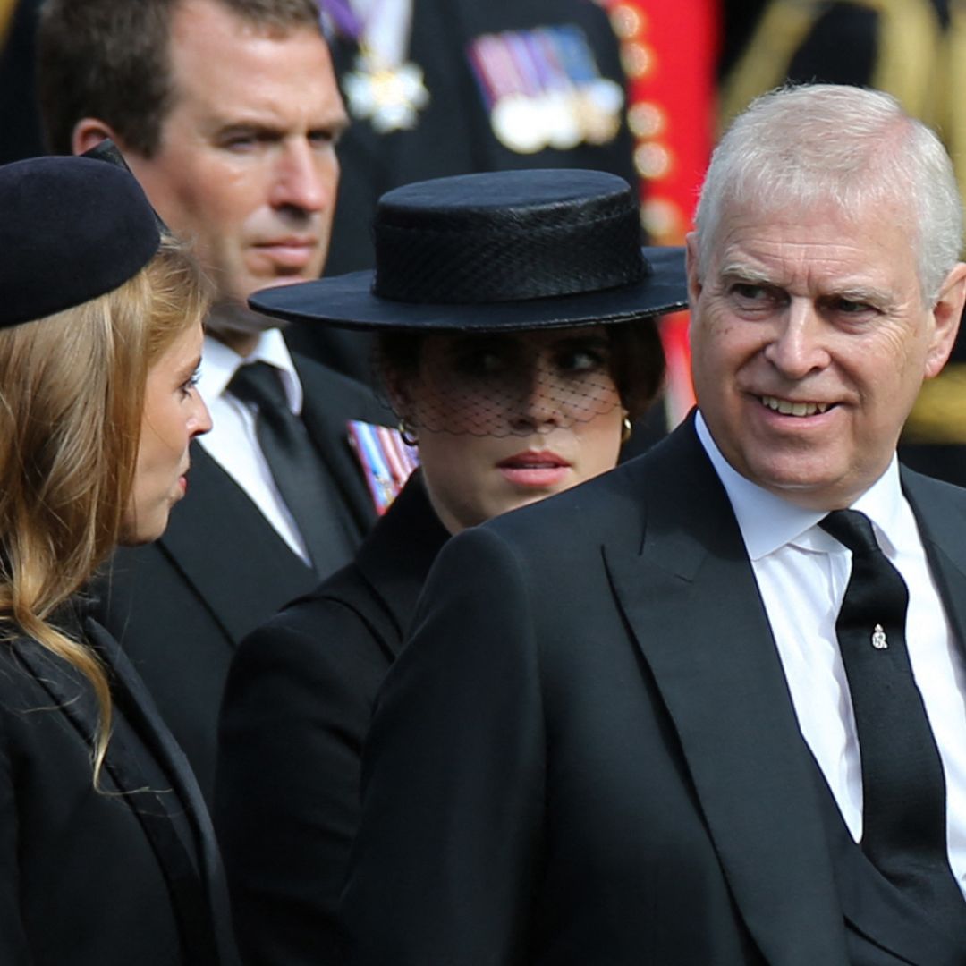 Princess Beatrice and Princess Eugenie wearing black hats and coats standing next to Prince Andrew who is smiling and wearing a black suit with military medals