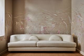 Cream coloured modern sofa in front of painted wallpaper