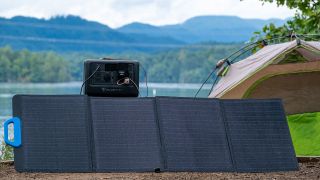 A BLUETTI EB3A sits atop solar panels by a lake.