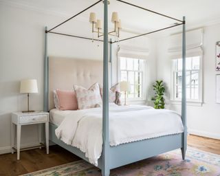 white bedroom with four poster blue bed and pink headboard