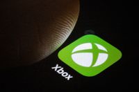 Xbox logo on a smartphone screen with a thumb hovering over it