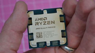 An AMD Ryzen 9 7950X3D held between a man's fingers