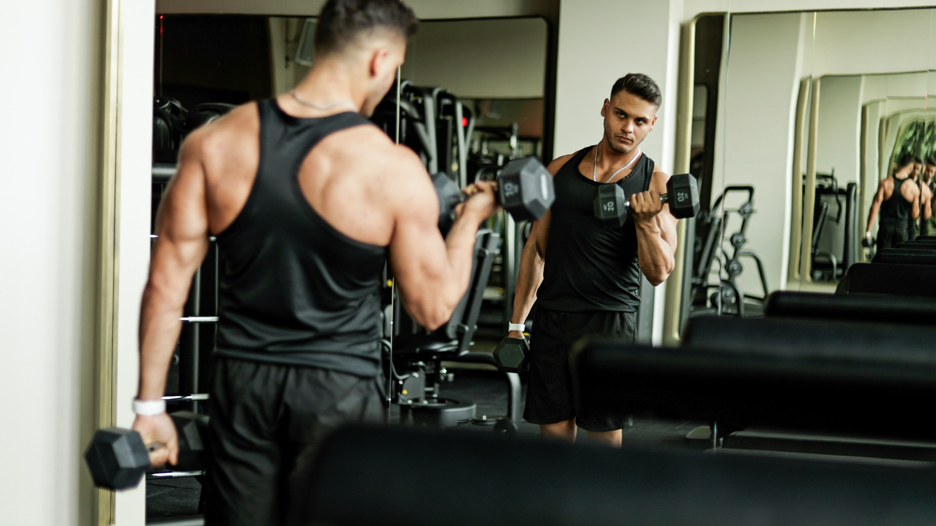 A man doing bicep curls whilst looking in the mirror 