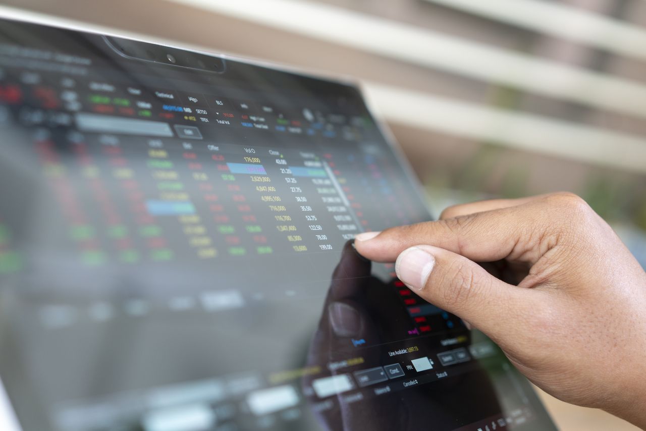 closeup of person using finger to look at small numbers on stock screen