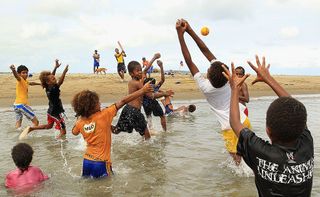 Kids play catch in the water at Mele Beach on May 16, 2012, in Port Vila, Vanuatu.
