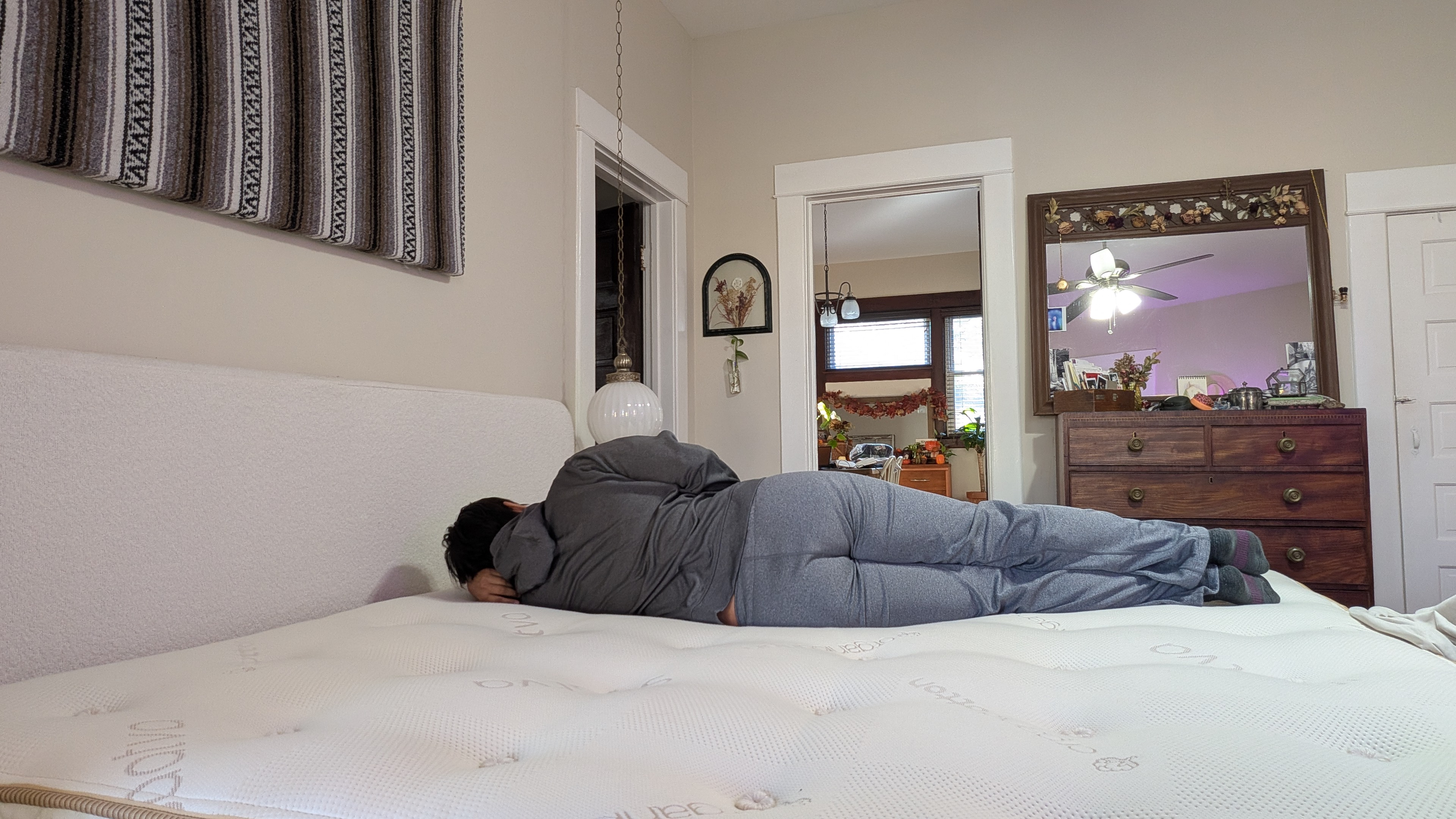 Mattress tester Alex laying on the Saatva Latex Hybrid Mattress on her side to show its level of comfort and support in that position