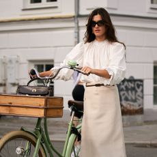 woman pushing bicycle wearing pretty blouse and skirt