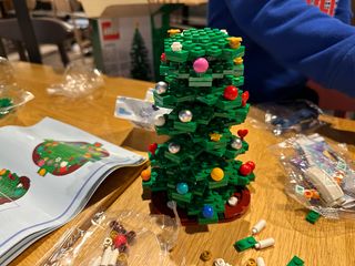 Christmas Tree Lego layers built on a wooden table with Lego pieces surrounding it