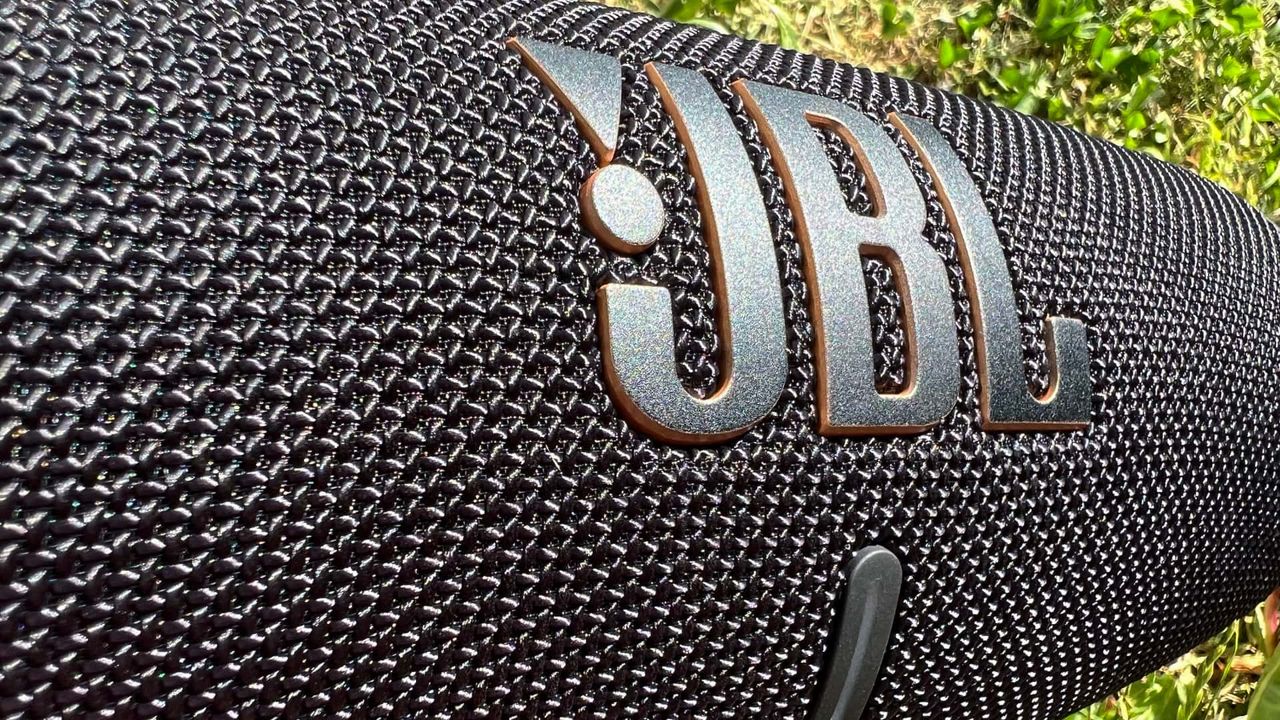 JBL Charge 5 Wifi med gr&auml;smatta i bakgrunden