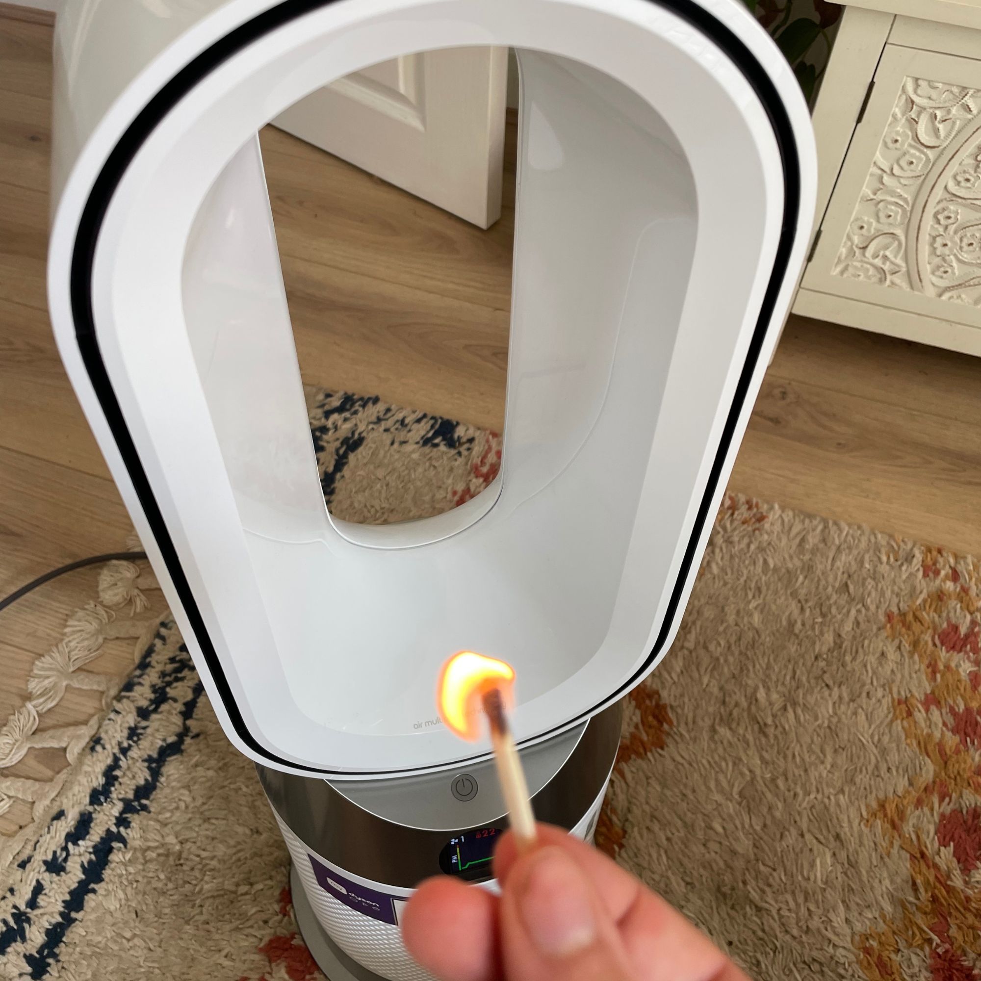 Hand holding a match in front of the Dyson Purifier Hot+Cool HP1 Purifying Fan Heater