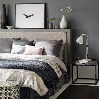 bedroom with grey coloured wall black rug and wooden headboard