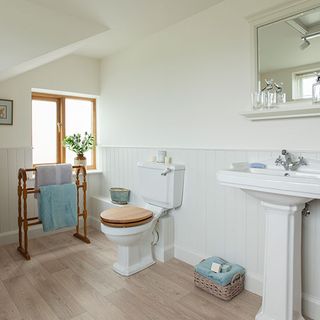 bathroom with white wall and wooden floor and toilet and towel rack