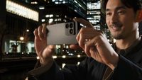 Sony Xperia 1 VIII held up by a person taking a photo in front of a nighttime cityscape