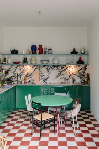 A glossy green kitchen with red chequerboard floors and vintage furniture