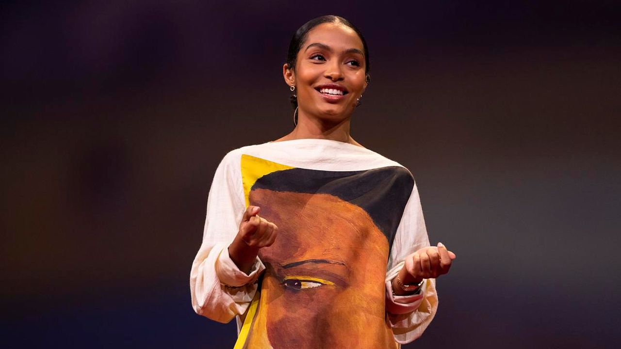 a woman (yara shahidi) wearing a painted dress gives a ted talk