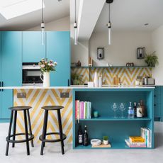 Kitchen with teal cabinetry and yellow and white tiled island with open shelving