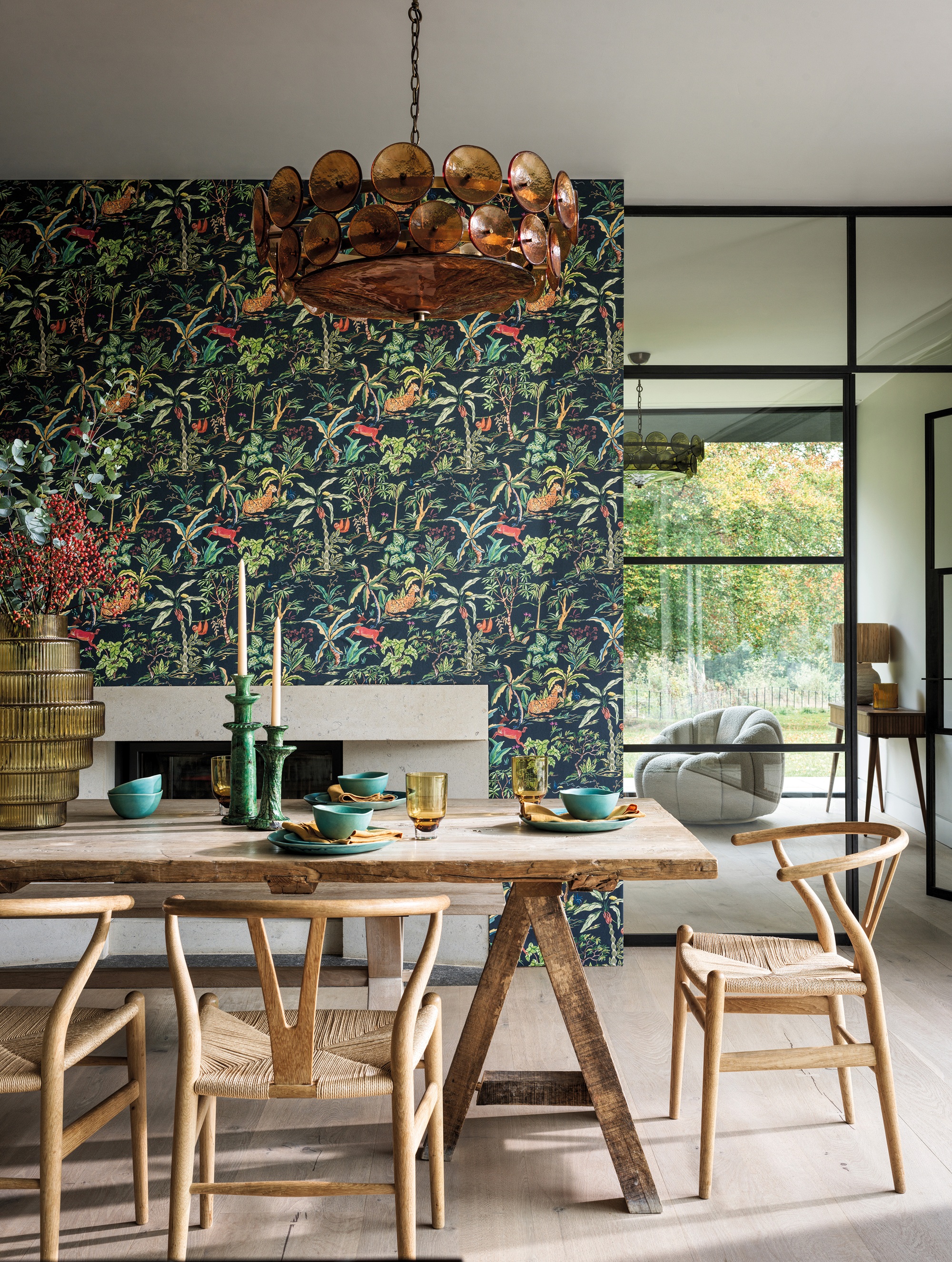 a dining room with patterned jungle wallpaper and a wooden dining table