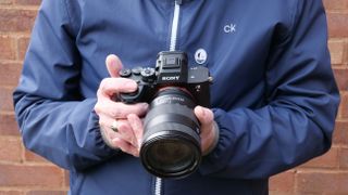 Sony A7R V being held chest height by a man in blue jacket