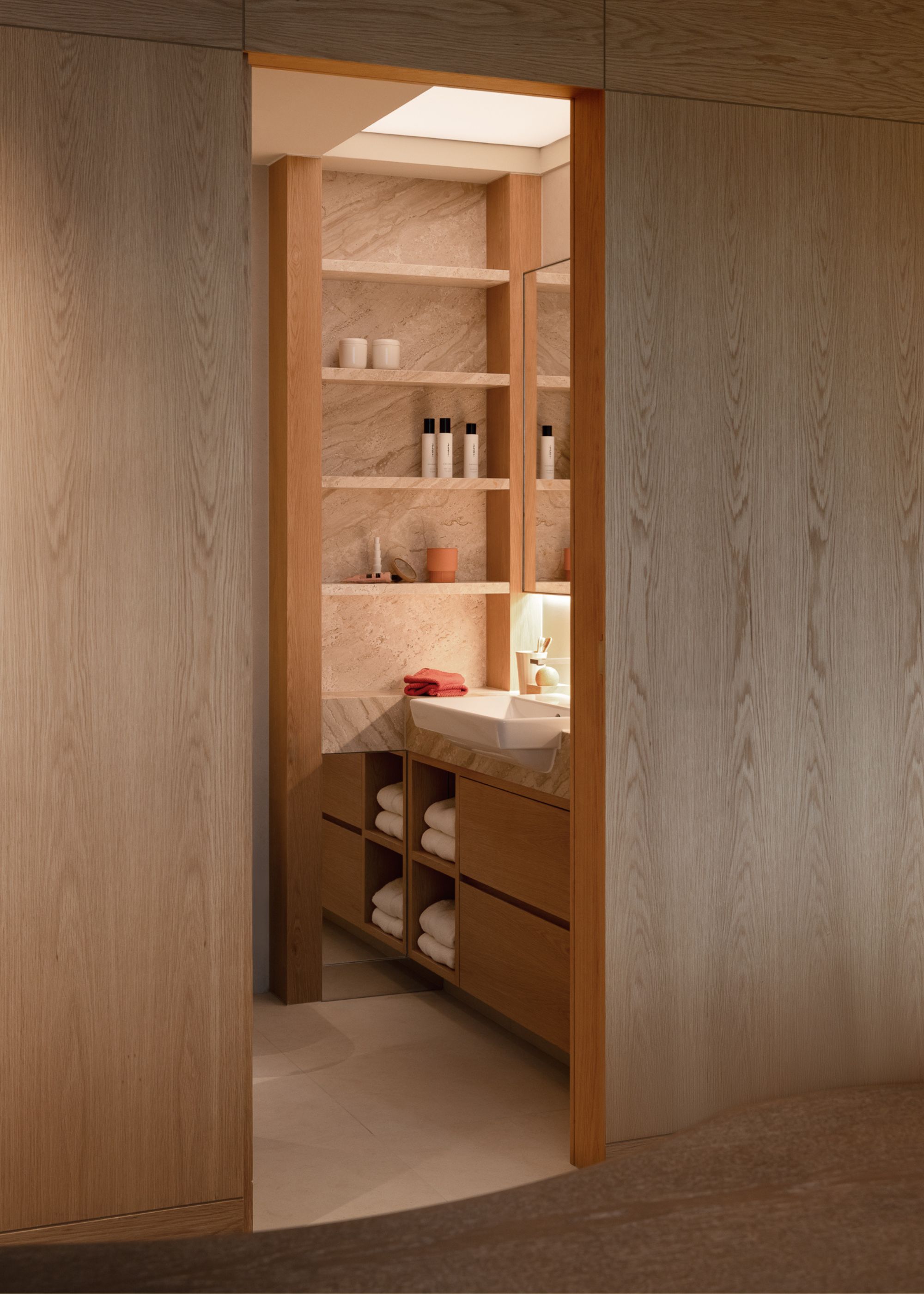 A peek into a minimalist bathroom with stone shelves and wood cabinets